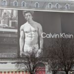 Photo d'une immense affiche recouvrant un immeuble parisien où l'on voit l'acteur Jérémy Allen White torse nu pour promouvoir les sous-vêtements de la marque Calvin Klein.