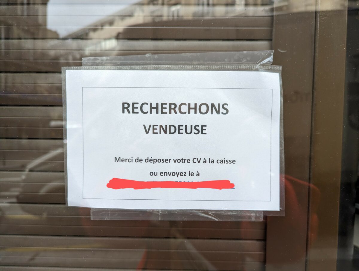 Petite annonce sur la vitrine d'un magasin où on lit "Recherchons vendeuse"