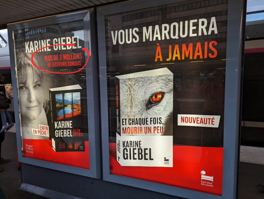 Double affichage pour le livre de Karine Giebel "Et à, chaque fois mourir un peu", dans les couleurs rouge et noir, avec la couverture du livre sur laquel on voit un oeil orange d'animal mençant. On lit "Plus de 2 millions de lecteurs conquis"