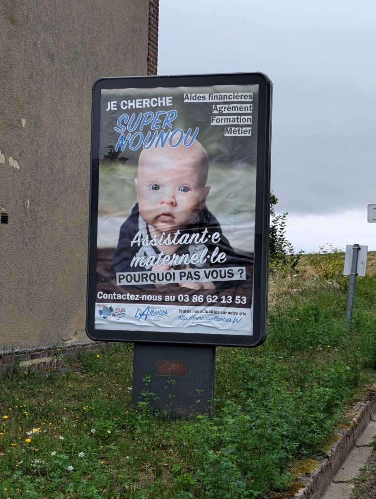 Affiche sur un bord de route représentant un bébé sur laquelle on peut lire : Assistant·e maternel·le, pourquoi pas vous ?